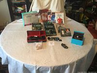 Lot arranged on round table showing DVDs, shaver, sunglasses, bracelet, and skincare set