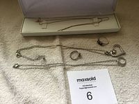 Full lot showing all chains and rings including gold chain in box and two silver chains with pendants and three rings.
