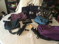 Photo showing seven handbags arranged on fabric background with curling iron and hair straightener cords coiled in front.