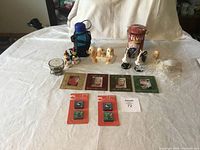 Full view of the Elvis Presley tin, assorted ceramic figurines, postcards, packets of cloth patches, water bottle and candle holder displayed on table.