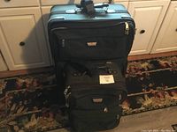 Two black Air Canada luggage pieces stacked in front of kitchen cabinets, showing the front and side views