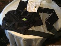Shows assortment of men's clothing items including black long sleeve shirt, white t-shirt, and black/grey pullover sweatshirt.