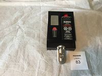 Front view of Zippo lighter set including lighter, lighter fluid, and replacement flints displayed in a black plastic tray on white cloth background.