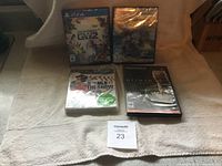 Four video game cases on a beige surface: two PS4 games (Plants vs Zombies GW2, RIGS), one PS3 game (MLB 13), and one PS2 game (Hitman).