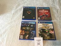 Four PS4 game cases laid out, showing front covers of Batman Return to Arkham, Spider-Man, Arkham Knight, and Monster Jam Steel Titans 2.