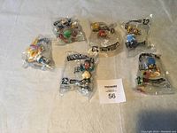 Set of 6 Simpsons collectible figurines in original sealed plastic packaging on a white background with a maxsold lot card