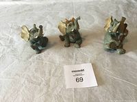 Photo showing three soapstone elephant figurines in different poses on a white cloth.