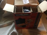 Photo of open original box showing Proctor Silex Belgian waffle maker packaging with waffle maker inside and protective cardboard compartments.