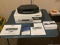 Wave Music System III, Wave III Dock box, manuals and remote arranged on folding table