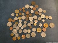 Photo showing about 60 foreign coins spread out on a surface, varying sizes and metal colors.