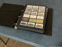 Black binder open showing a page with rows of matchbook labels with varied designs and text