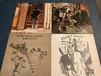 Four Bob Dylan vinyl records with distinct album covers showing various artistic styles and photos.
