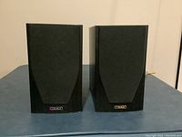 Front view of two black Mission M71 speakers with front grills on.