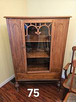 Front view of walnut china cabinet with decorative fretwork on glass door and turned feet