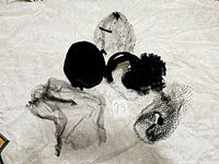 Full view of four vintage headpieces laid out on bedspread showing various veils and hats.