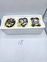 Set of three vintage Ashton Drake Christmas ornaments in original white styrofoam packaging, showing overall lot presentation.