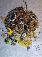 Full view of assorted vintage jewelry pieces showing a mix of necklaces, bracelets, brooches, rings, and earrings in different colors and materials.