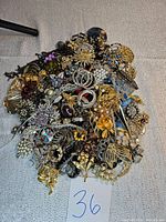 Overview of the pile of assorted vintage jewelry items including brooches, clips, earrings, and bracelets in various metallic tones and designs