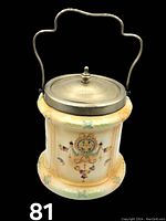 Front view of signed porcelain biscuit jar showing detailed colorful floral and bow designs with metal lid and knob, and metal handle.