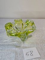 Side view showing the thick glass and flowing organic shape with green accents.