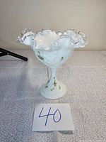 Front view showing ruffled clear glass edge and floral handpainted details on white milk glass compote.