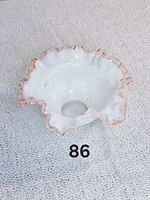 Top view of a white milk glass bowl with pink ruffled crest edge, showing the interior and wavy rim design.