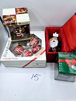 Photo showing four boxed vintage Christmas ornaments including candy cane shapes, Santa Claus, novelty black ornament, and red bell-shaped ornament.