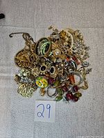 Full view of vintage jewelry lot with various brooches, necklaces, and earrings in gold and silver tones, some with pearls and rhinestones