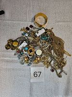 Overview photo showing the full assortment of vintage costume jewelry including chains, brooches, earrings, a cuff bracelet, and pearl strands.