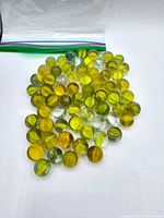 Photo showing approximately 60 vintage marbles mostly yellow-green in glass.