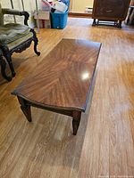 Angled side view of wood coffee table showing carved legs and wood grain pattern on tabletop.