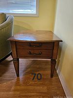 Front view of the wood side table showing two drawers with handles, chevron patterned wood top, and tapered legs.