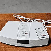 White Bose Wave Radio top view with control buttons and power cord visible, placed on wooden surface.