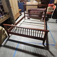 Photo showing the full wooden bed frame from the footboard end, highlighting the rectangular frame and slatted footboard design.