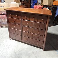 Front and side view of the wooden dresser showing ten drawers and round wooden knobs, with a medium brown finish.