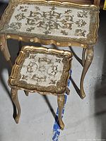 Both decorative tables shown stacked, highlighting size difference and ornate details.