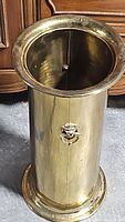 Side view showing cylindrical brass body with lion head handle and ring on one side.