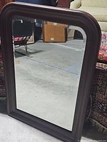 Full view of the large vintage mirror showing the rectangular shape with rounded corners and brown wooden frame.
