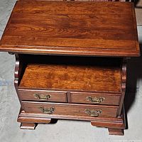 Top view of vintage wooden nightstand showing the surface and the two drawers with brass handles and open shelf below the top.