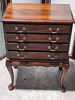 Front view of four-drawer cabinet with brass bail handles and cabriole legs