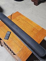 Yamaha sound bar placed on a wooden table, showing the full front speaker mesh and slim design.