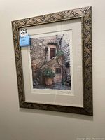 Front view of framed photographic print showing stone staircase and potted plants in rustic setting.
