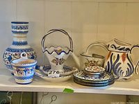 Shelf display of ceramic vases, plates, and planters with hand-painted floral patterns and varied shapes