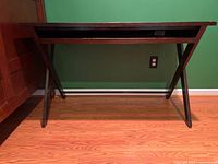 Wood computer desk viewed from the front, showing the pull-out keyboard drawer closed.