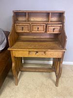 Front view of pine wood writing desk showing three upper drawers and three cubby slots, along with one lower drawer.