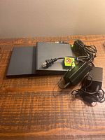 Two AT&T DIRECTV Genie digital TV boxes with power adapters on a wooden surface.