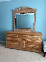 Photo of the wooden dresser with attached mirror, showing the front view and reflective mirror attached to the top.