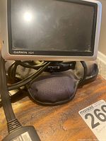 Garmin Nuvi GPS unit with attached cabling on fabric surface, showing front screen and branding.