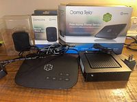 Overview of all components including Ooma Telo base unit, Ooma Linx remote phone jack in packaging, Motorola modem, power cords, and box with manual.