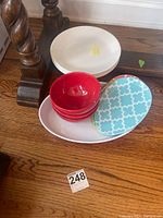 White Corelle plates stacked; three red bowls stacked; three blue and white Easter egg shaped plates with yellow rim stacked.